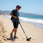 A person using a metal detector on a San Diego beach